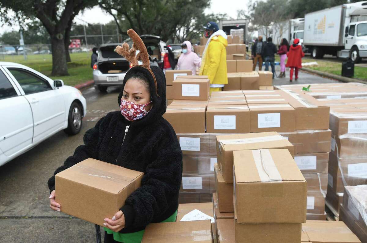 Volunteers, including Naomi Hernandez, help distribute holiday food boxes filled with produce and essentials and turkeys during a Southeast Texas Food Bank holiday distribution Monday in Port Arthur. In all, 500 turkeys and boxes were given out to help families this holiday season. Photo made Monday, December 20, 2021 Kim Brent/The Enterprise