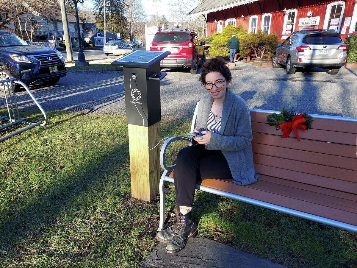 Kent Memorial Library staff member Debbie Moerschell makes use of the library’s new solar powered table with charging ports.