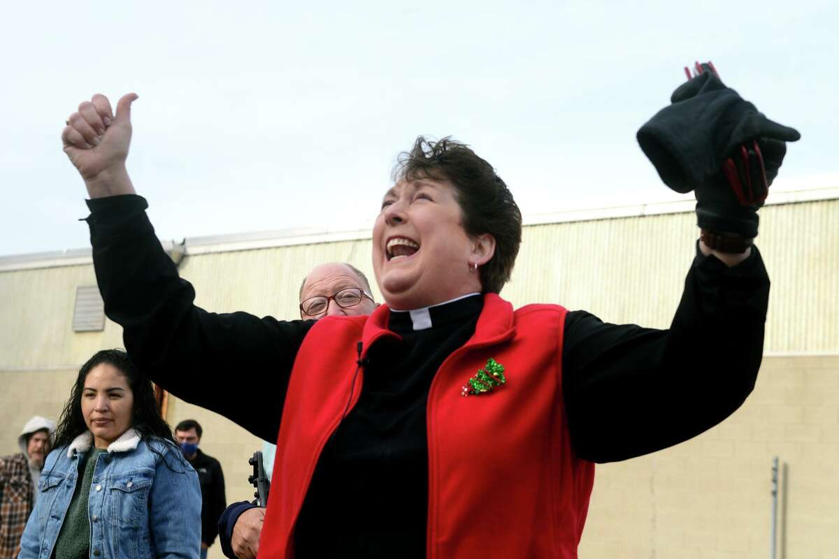 Rev. Sara Smith, founder and CEO of nOURish Bridgeport, cheers as she watches a crane move a new shipping container into place next to the hydroponic farm currently under construction in Stratford, Conn. Dec. 21, 2021. The farm will grow and supply fresh vegetables for those in need in the greater Bridgeport area.