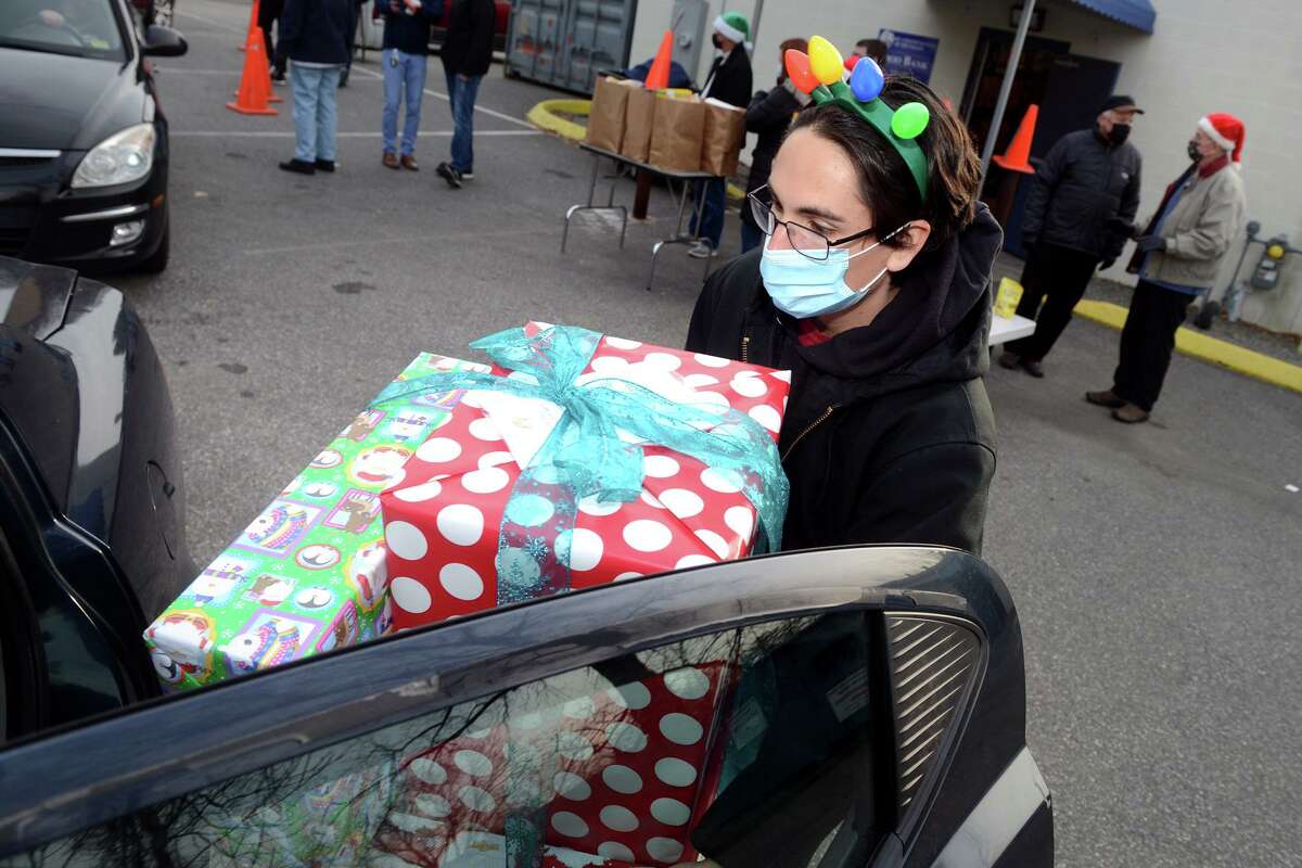 Volunteer Ralph Venezia loads presents into a waiting car during St. Vincent de Paul Food Bank’s holiday food and present pickup in Derby on Tuesday.