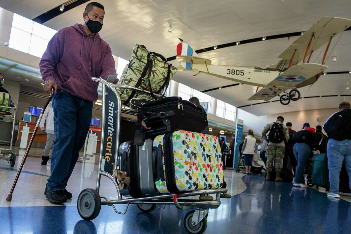 A man rolls a cart of luggage through Terminal B at San Antonio International Airport in San Antonio, Texas, on Dec. 21, 2021.