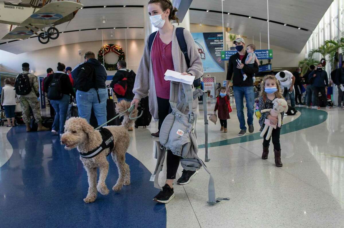Jenn Milot and her service dog Addison lead her family through the San Antonio International Airport in San Antonio, Texas, on Dec. 21, 2021.