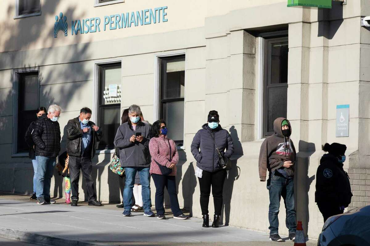 People with vaccine booster appointments line up outside of Kaiser Permanente on Geary Boulevard in San Francisco on Tuesday, amid warnings about the omicron wave.