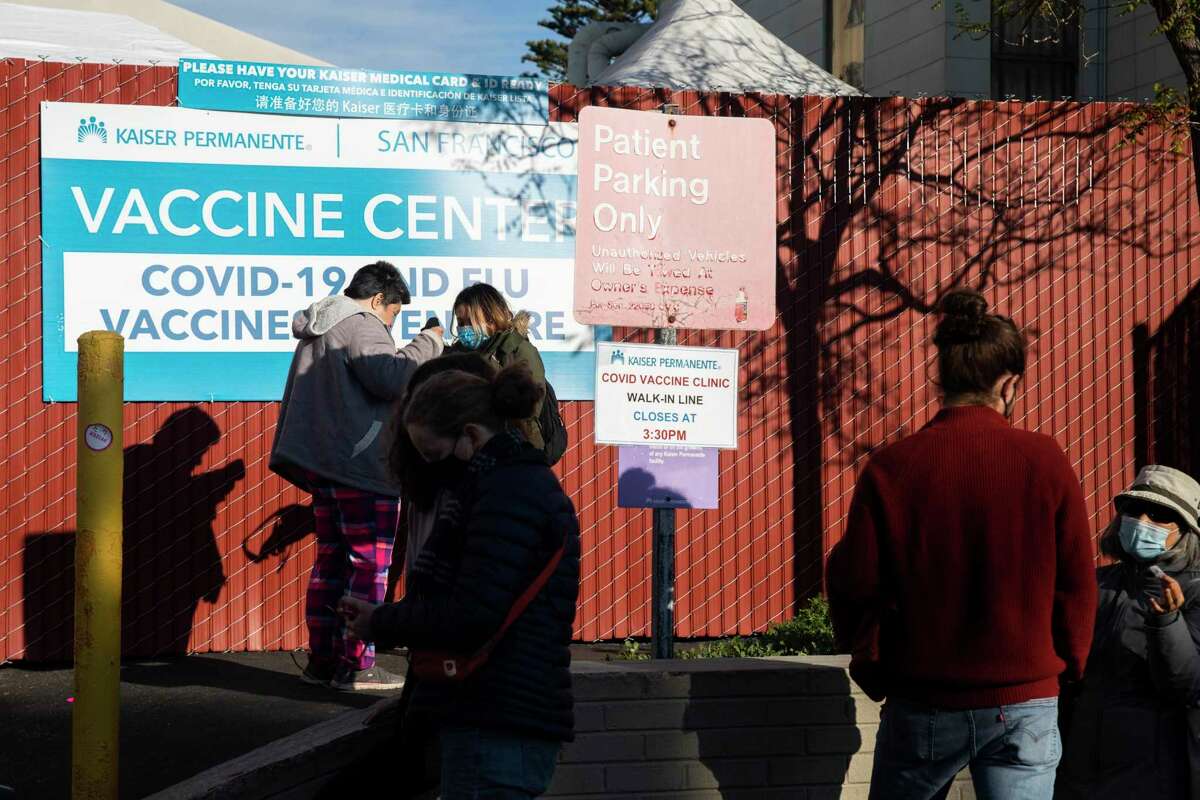 People line up to receive a COVID-19 booster shot at Kaiser Permanente on Geary Boulevard in San Francisco on Dec. 21. Health officials are urgently recommending that everyone eligible get a booster to help fend off omicron.