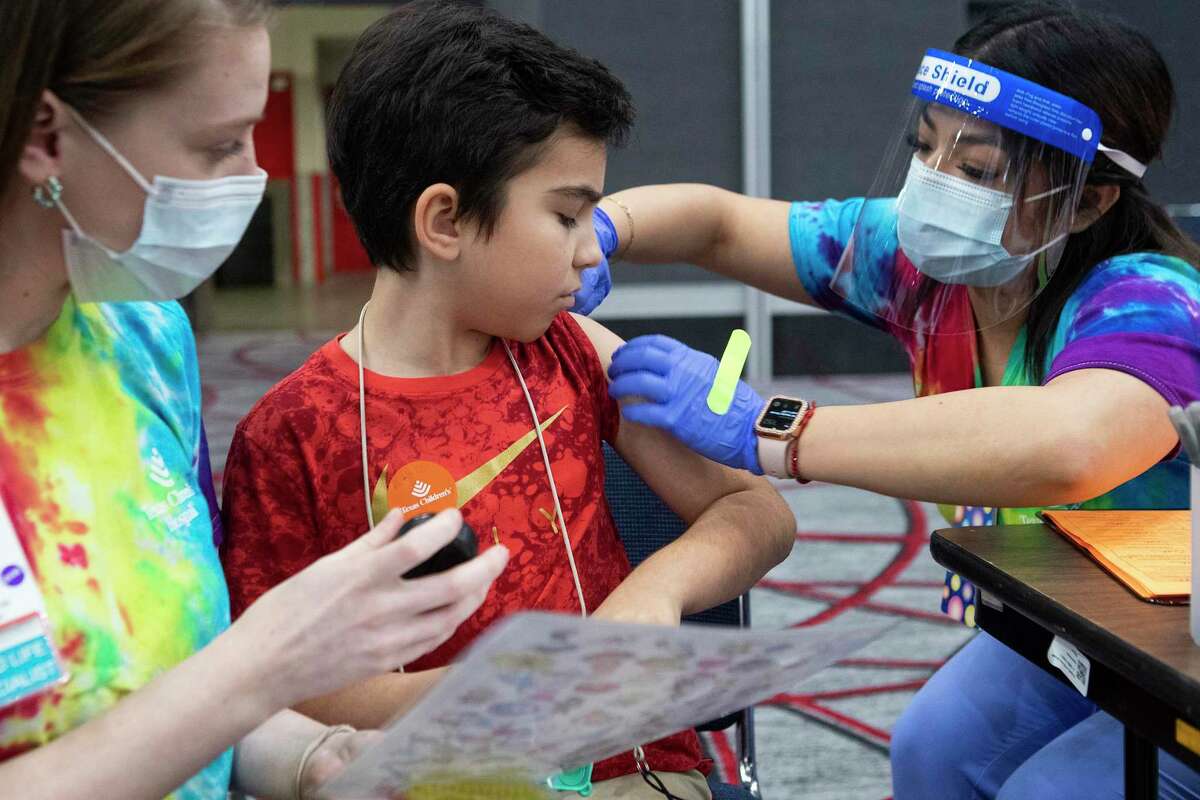 Ashley Clark, left, and Cinthia Rivera prepare Levi Thornhill for his vaccination Friday in Houston.