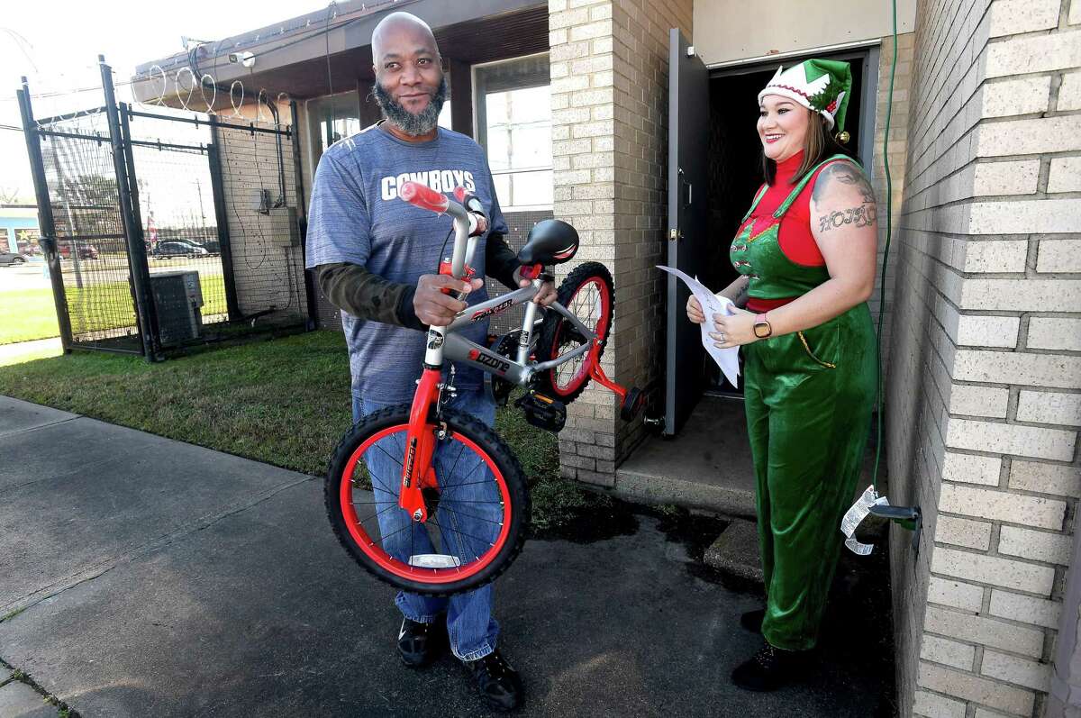 Rachell Johnson smiles as Larry Gatlin carries out a bicycle for one of his children during the United Steel Workers Union Local 13-243's holiday event at the hall Tuesday. Families enjoyed lunch and entertainment while picking up toys for their children and holiday items from the food pantry. Photo made Tuesday, December 21, 2021 Kim Brent/The Enterprise