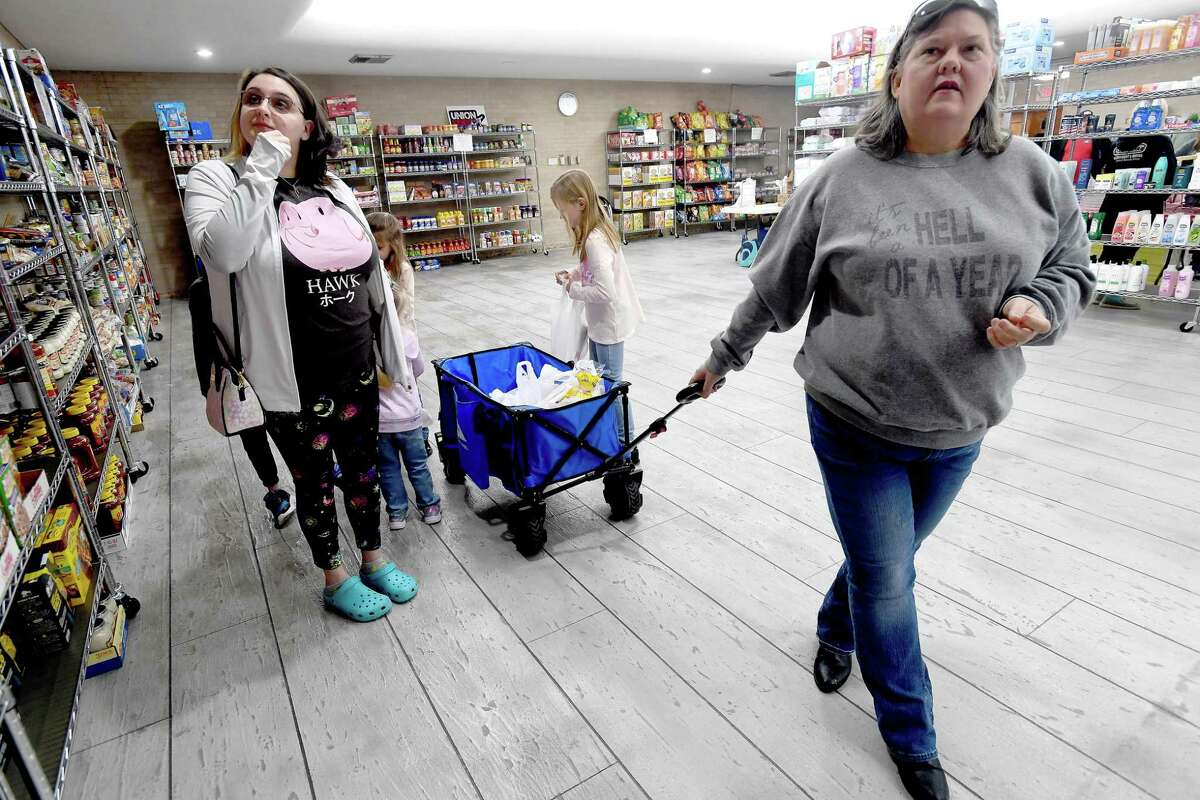 Tabitha King (left) and mother-in-law Cyndi Herrington make their way through the pantry shelves picking up supplies for the holiday during the United Steel Workers Union Local 13-243's holiday event at the hall Tuesday. Families enjoyed lunch and entertainment while picking up toys for their children and holiday items from the food pantry. Herrington's husband is a 14-year employee at ExxonMobil who has been locked out forr nearly a year. The assistance from the union's food pantry and with monthly bills has helped them weather the storm. "They've been really good to us," she said, adding they look forward to a resolution and getting back to work. "It's like, is it ever going to end?" she said. Photo made Tuesday, December 21, 2021 Kim Brent/The Enterprise