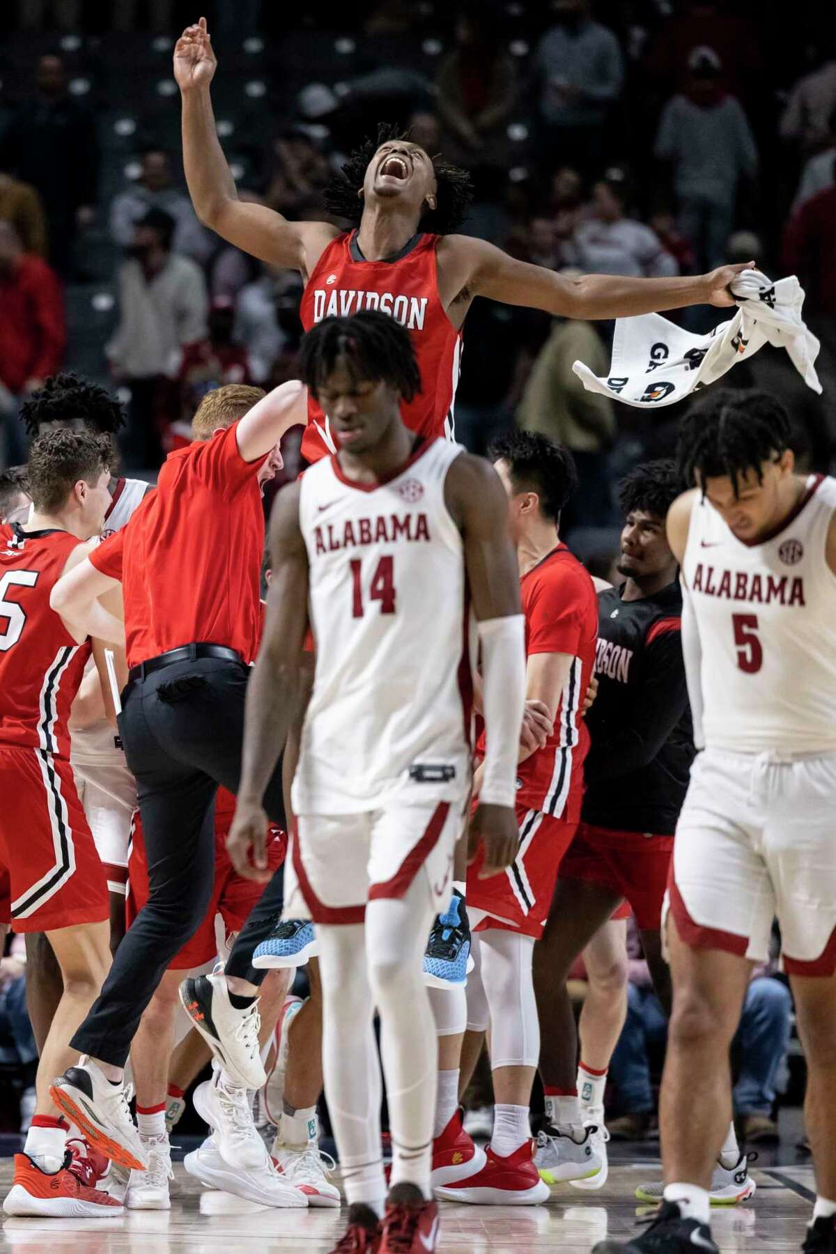 Davidson guard/forward Desmond Watson (4) leaps into the air to celebrate an upset of No. 10 Alabama in Birmingham, Ala. Also pictured walking off are Alabama guards Keon Ellis (14) and Jaden Shackelford (5).