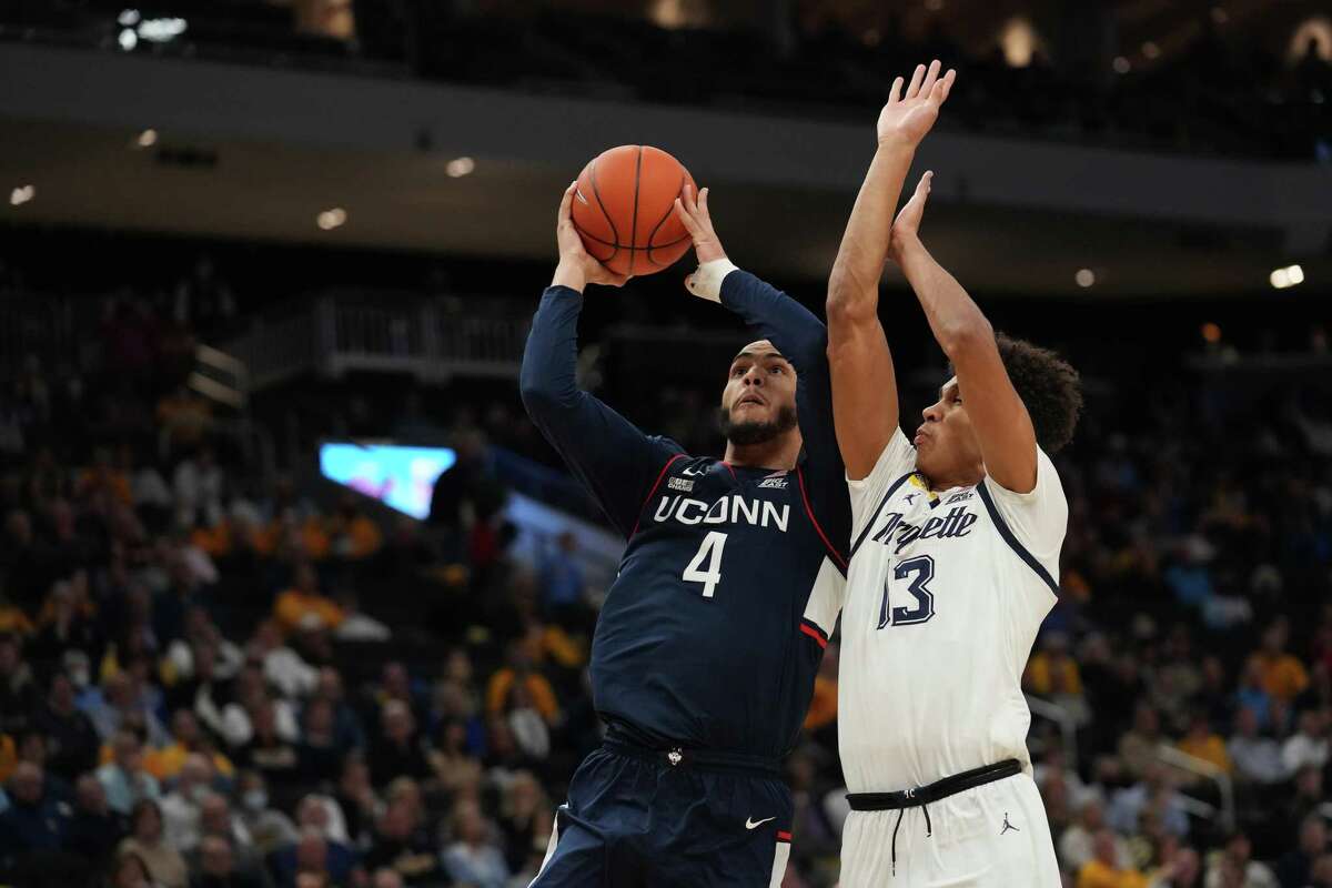 MILWAUKEE, WISCONSIN - DECEMBER 21: UConn’s Tyrese Martin (4) shoots the ball against Marqette’s Oso Ighodaro in the second half at Fiserv Forum on Tuesday in Milwaukee, Wisc. UConn won 78-70.