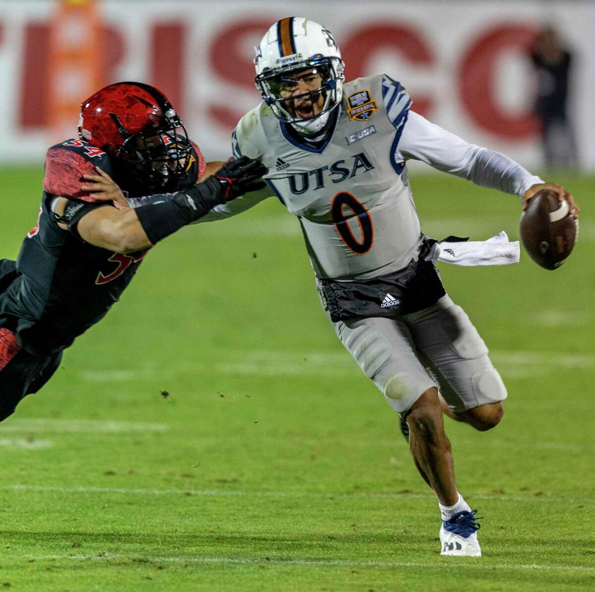 UTSA Roadrunners quarterback Frank Harris rushes Tuesday, Dec. 21, 2021 during the second half of the Tropical Smoothie Cafe Frisco Bowl in Frisco, Texas around San Diego State Aztecs linebacker Caden McDonald. San Diego State University beat the Roadrunners 38-24.