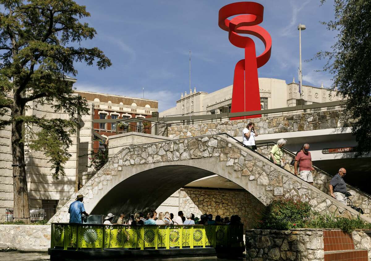 People ride on a GO RIO riverboat as others others walk along the River Walk near the La Antorcha de la Amistad sculpture in Downtown San Antonio, Texas, Wednesday afternoon, Sept. 22, 2021. 