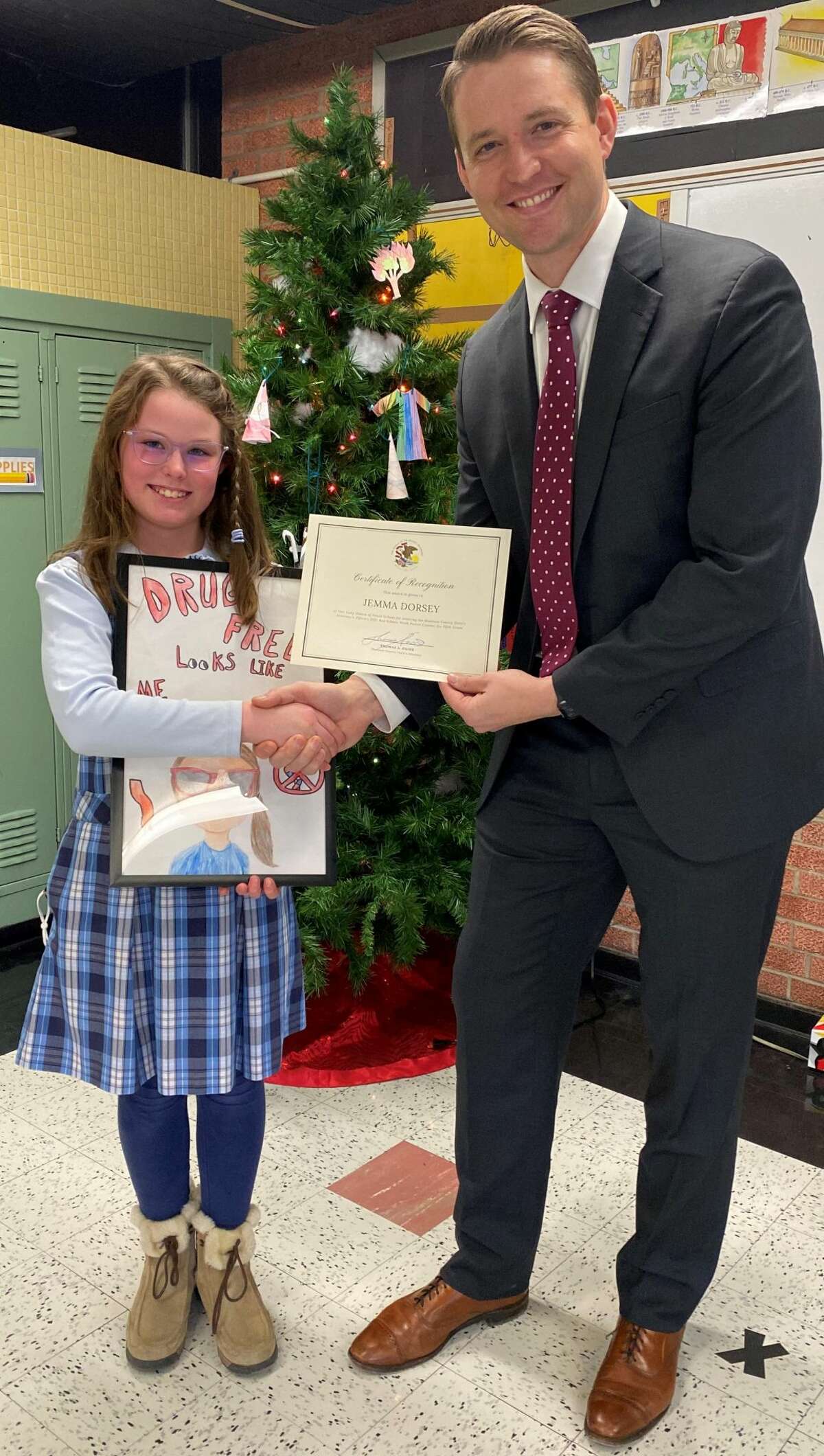 Fifth Grade Red Ribbon Week poster winner Jemma Dorsey of Our Lady Queen of Peace in Bethalto is congratulated by Madison County State's Attorney Tom Haine.