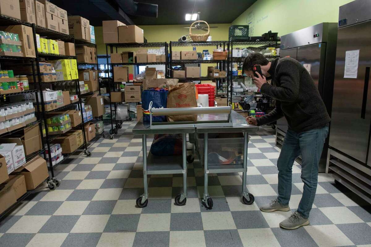 Executive Director Devin Bulger is seen taking an order over the phone at the Greenwich Food Center, a pantry which is part of Comfort Food Community on Monday, Dec. 13, 2021 in Greenwich, N.Y. The person he’s talking to on the phone is quarantined because of COVID. Comfort Food Community is a food bank that has grown from a small space in a church to a large operation that includes local farms.