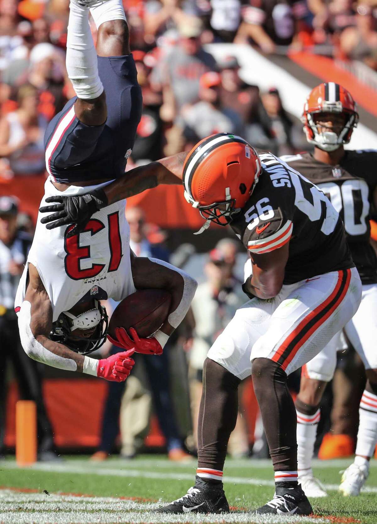 Houston Texans wide receiver Brandin Cooks (13) flips as he is hit by Cleveland Browns linebacker Malcolm Smith (56) after scoring on a 2-yard reception during the second half of an NFL football game Sunday, Sept. 19, 2021, in Cleveland.