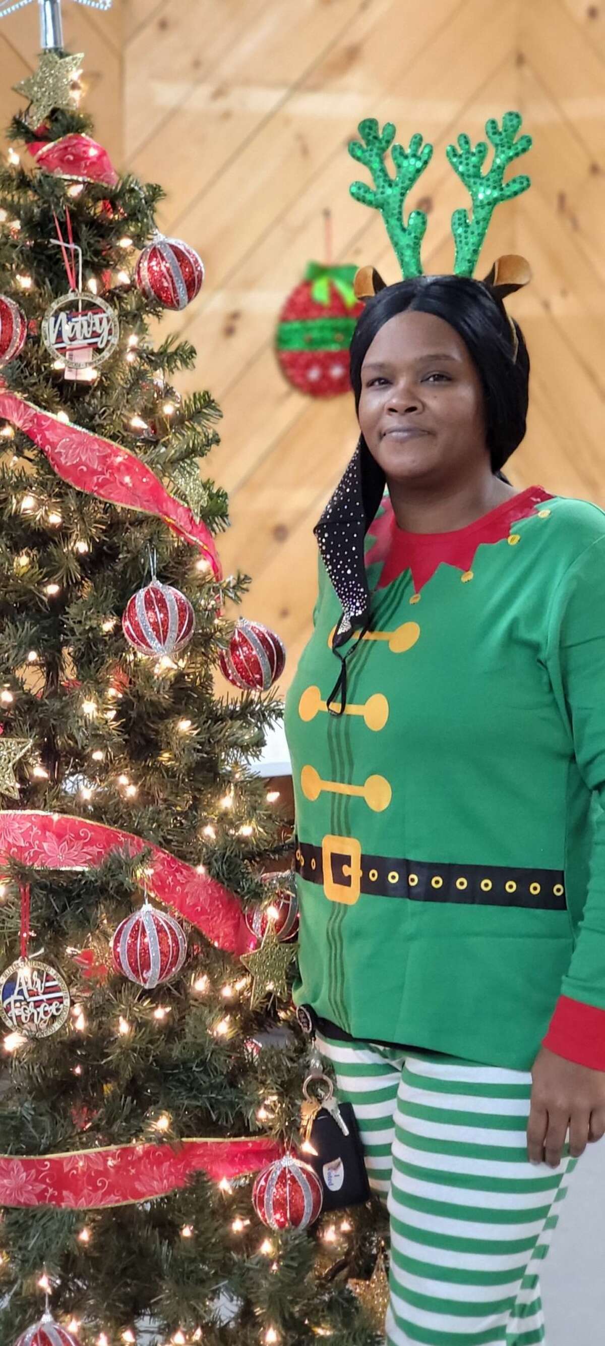 LaShawn Hawkins poses with a Christmas Tree dressed as one of Santa's Elves