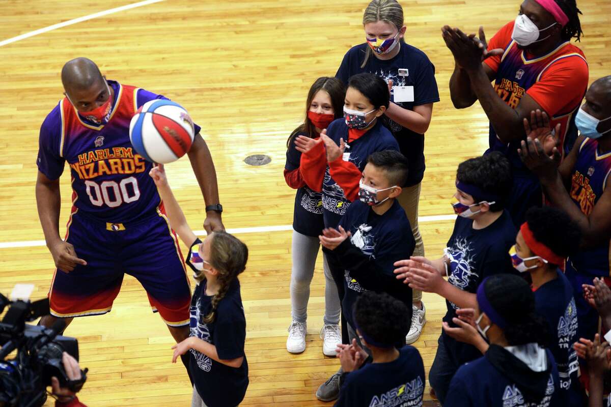 Ansonia school students learn basketball tricks from Dwayne “Swoop” Simpson of the Harlem Wizards basketball team prior to a rededication ceremony in the newly renovated Ansonia Armory gymnasium, in Ansonia, Conn. Dec. 22, 2021.
