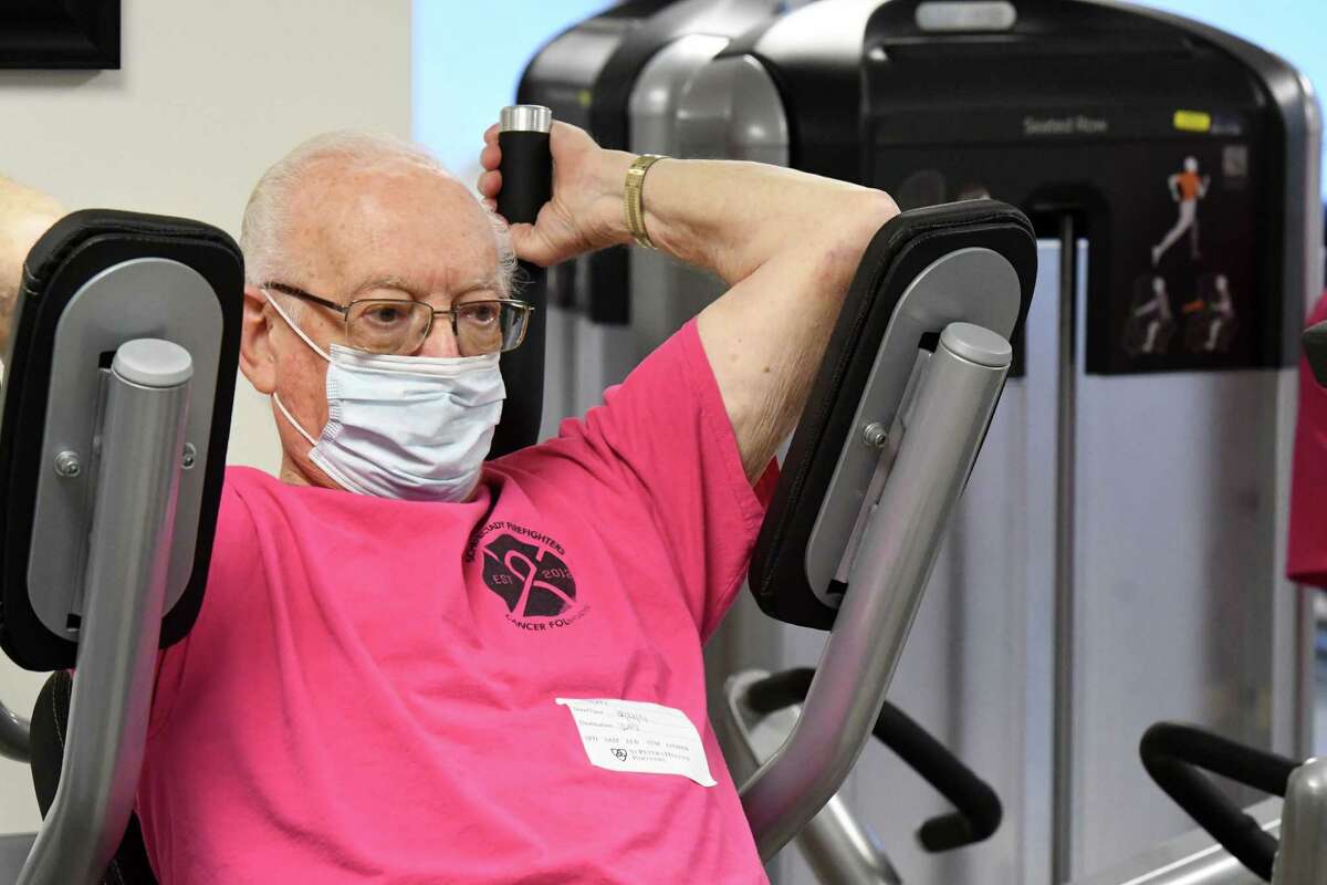 Wearing a pink caner awareness shirt, Bob Sweet works out in the gym at Sunnyview Rehabilitation Center on Wednesday, Dec. 22, 2021, in Schenectady, N.Y. Bob is part of a group of elderly people who, for the past few years, have been working out together. They wear pink Schenectady City firefighter shirts to promote cancer awareness. Some of them are cancer survivors, while others do it to stay in shape and in honor of family members who had/have cancer.