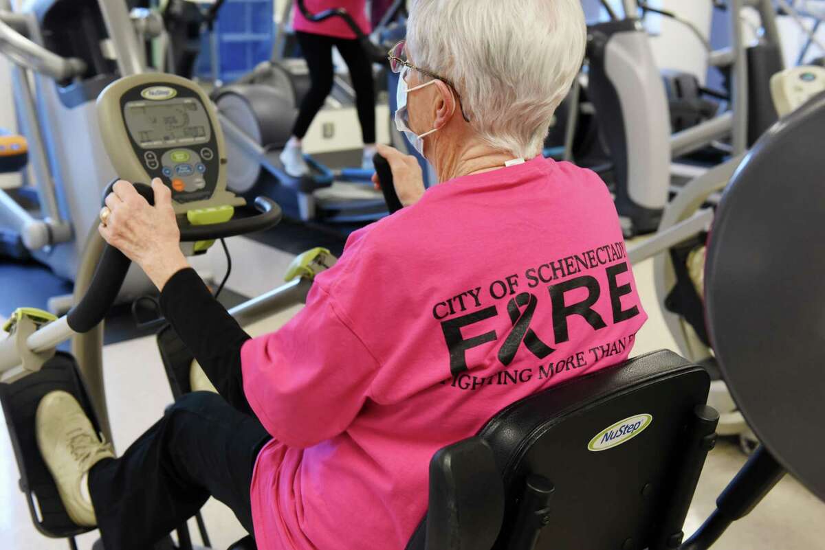 A group of of cancer awareness supporters workout in the gym at Sunnyview Rehabilitation Center wearing pink Schenectady City firefighter shirts to promote cancer awareness on Wednesday, Dec. 22, 2021, in Schenectady, N.Y. Some of them are cancer survivors, while others do it to stay in shape and in honor of family members who had/have cancer.