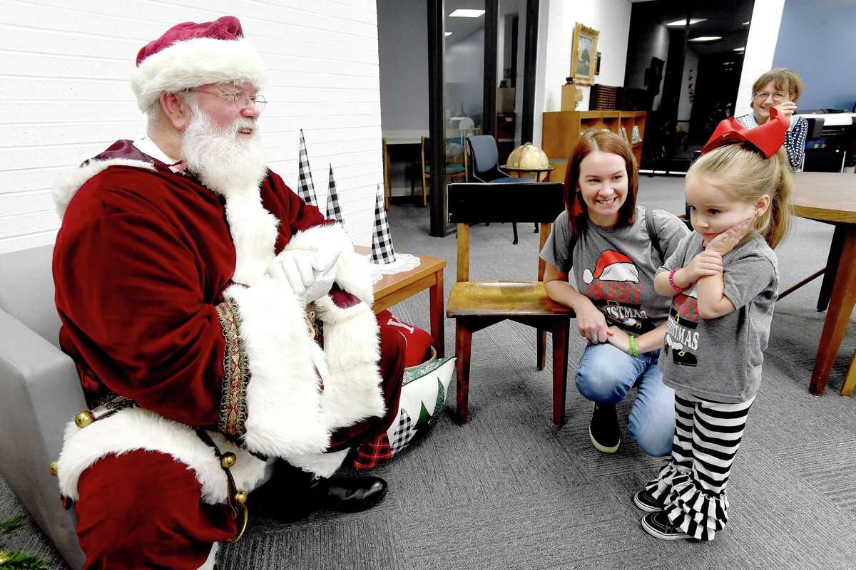 Santa tries to invite a wary Amelia Teran closer for a photo as mom Dana Teran looks on at the Effie & Wilton Hebert Library in Port Neches Thursday morning. The free family event ran in conjunction with a food drive to benefit the Southeast Texas Food Bank that runs through the end of the month. Photo made Thursday, December 16, 2021 Kim Brent/The Enterprise