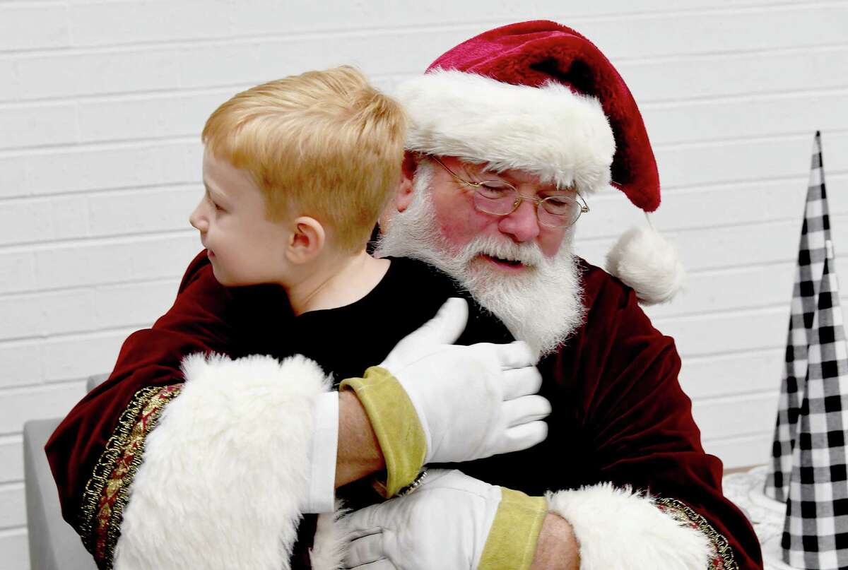Santa gets a hug from William Kohl before taking photos at the Effie & Wilton Hebert Library in Port Neches Thursday morning. The free family event ran in conjunction with a food drive to benefit the Southeast Texas Food Bank that runs through the end of the month. Photo made Thursday, December 16, 2021 Kim Brent/The Enterprise