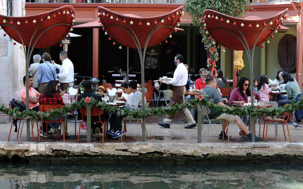 A waiter tends to tables as visitors roam and dine along RiverWalk on Wednesday, December 22, 2021. An Omicron variant of COVID-19 has been detected in Bexar County as people begin to travel and celebrate the Christmas holidays.