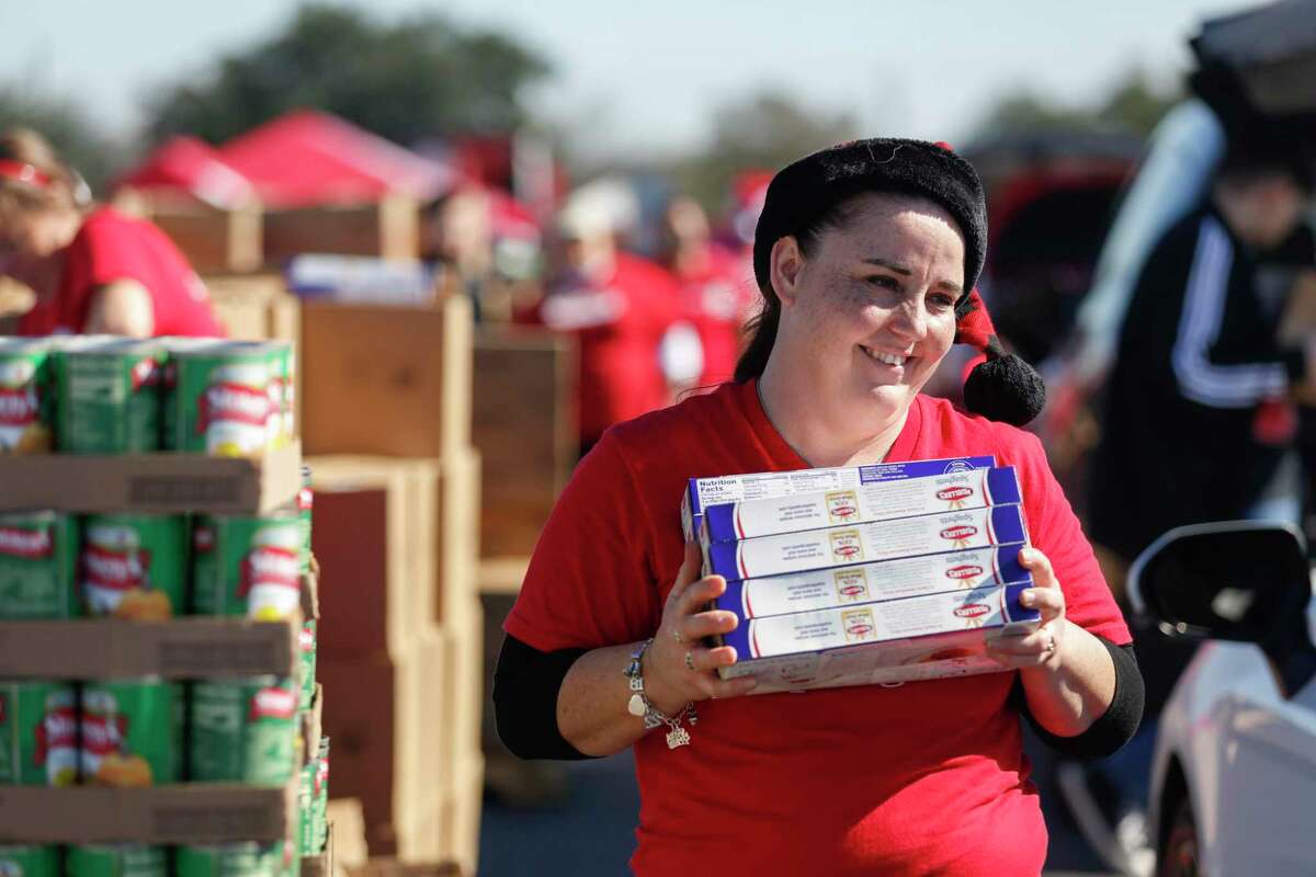 Misty Garza delivers boxes of pasta to people waiting in line during the H-E-B Feast of Sharing food distribution event at AT&T Center in San Antonio on Wednesday afternoon.