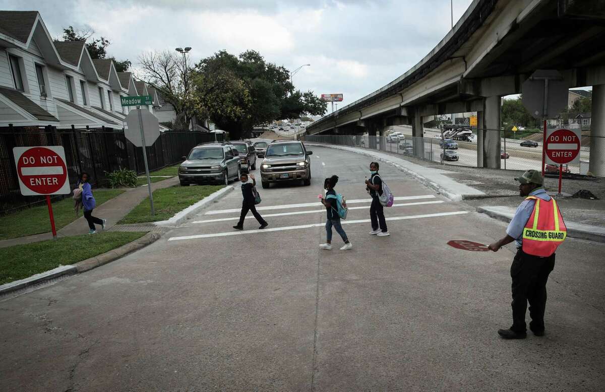 Children cross a feeder road along I-10 on Friday, Dec. 10, 2021, near Kelly Village, a Houston Housing Authority housing complex, in Houston. Children use the route to travel to and from Bruce Elementary School nearby, across the freeway. Residents and advocates are concerned about proposed changes to the I-45 corridor.