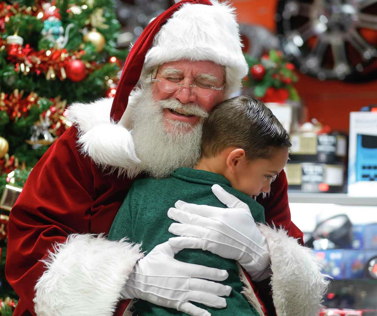 Nathan Arrazate, also known as Santa Nate, gets a hug from a young boy during a visit to CC Plus Trucks, Guns and Ammo, Thursday, Dec. 23, 2021, in Conroe.