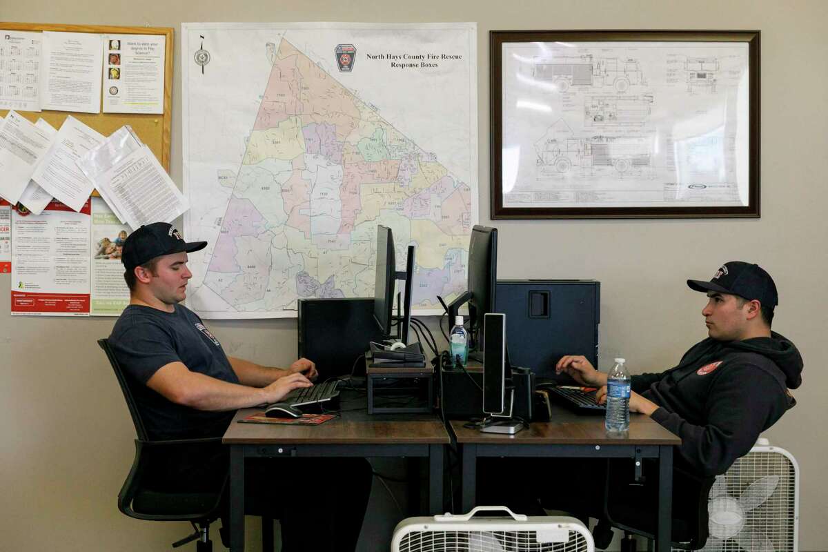 North Hays County Firefighters Eric Huggins, left, and Jonathan Pacheco work on computers in their living quarters at the North Hays County Central Fire and Rescue station located on Sportsplex Drive in Dripping Springs, Texas, Tuesday, Dec. 21, 2021. The firefighters work 48 hour shifts so fire station becomes their second home as they wait for emergency calls.