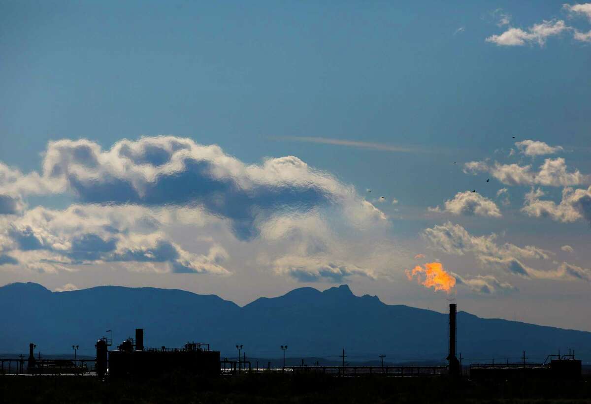 Mountains tower in the background as flames shoot from the flare stack of an oil production facility in Texas. Securities and Exchange Commission Chairman Gary Gensler has asked the agency’s staff to develop a proposal on climate-change disclosure by the end of this year. (Ryan Michalesko/Dallas Morning News/TNS)