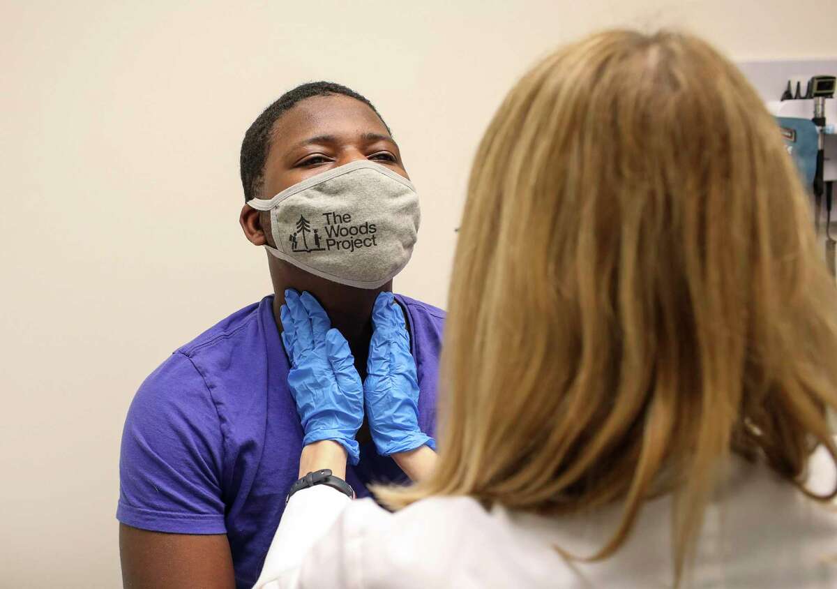 Adonye Williams, 16, gets a brief exam by Amy Starr, a family nurse practitioner, as part of a Moderna vaccine trial Saturday, Feb. 13, 2021, at CyFair Clinical Research Center in Houston.