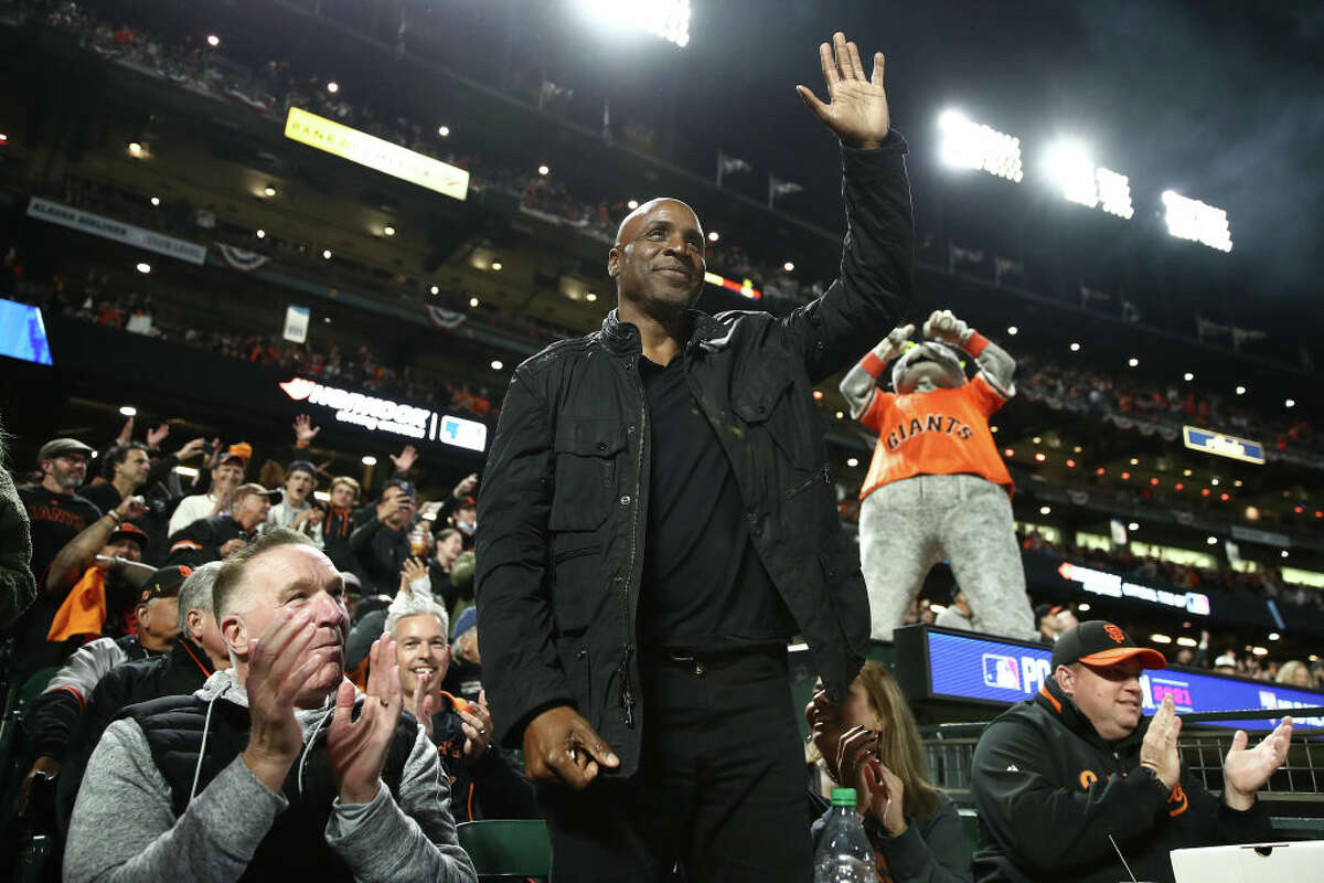 Former Warriors player Chris Mullin and former San Francisco Giants player Barry Bonds wave to the crowd during the fifth inning of Game 1 of the National League Division Series against the Los Angeles Dodgers at Oracle Park on October 08, 2021 in San Francisco, California.