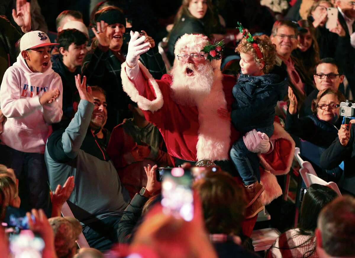 Santa Claus carries a young adorer as he makes an entrance during the 2021 Ford Holiday River Parade at the Arneson Theater on Friday, Nov. 26, 2021.