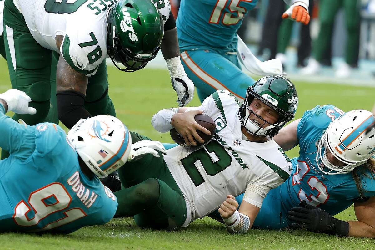 Zach Wilson #2 of the New York Jets is tackled by Emmanuel Ogbah #91 and Andrew Van Ginkel #43 of the Miami Dolphins in the third quarter at Hard Rock Stadium on December 19, 2021 in Miami Gardens, Florida