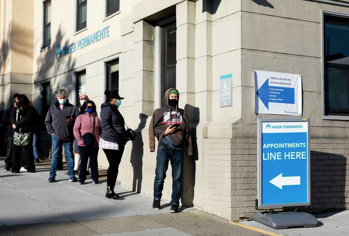 Vaccine booster appointments create lines outside Kaiser Permanente on Geary Boulevard in San Francisco. Health departments urge the public to get booster shots to blunt another surge.