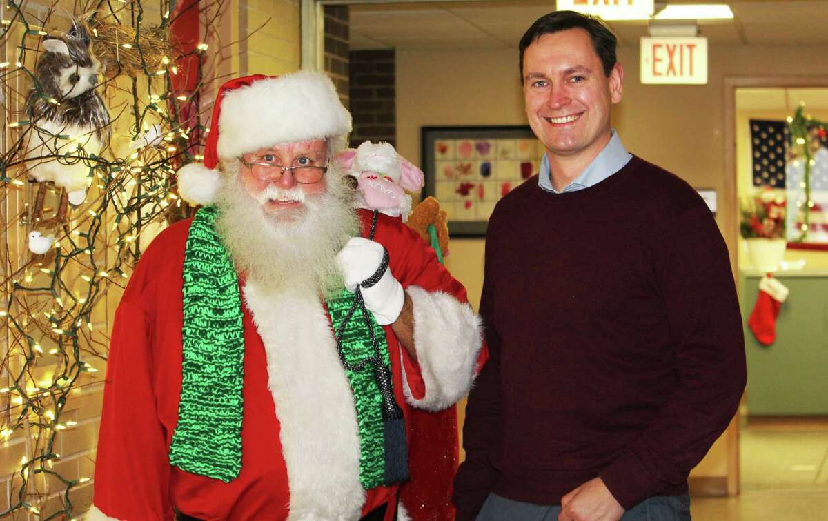 Santa Claus (Norman Ward of Portland) visited Middletown City Hall Thursday to spread holiday cheer to employees as part of a holiday door-decorating contest. The Land Use Department display was in honor of Weihnachten, a celebration of Christmas Eve in German-speaking countries. At right is Director of Land Use Marek Kozikowski.