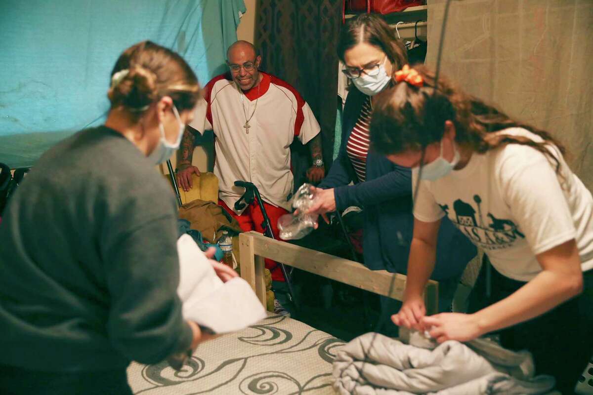 Ovidio Castro, 41, smiles as Cynthia Lafuente, 51, second from right, and her daughters, Laura, 25, left, and Sarah, 21, assemble a bed for Castro’s children at his apartment on the Southwest Side.