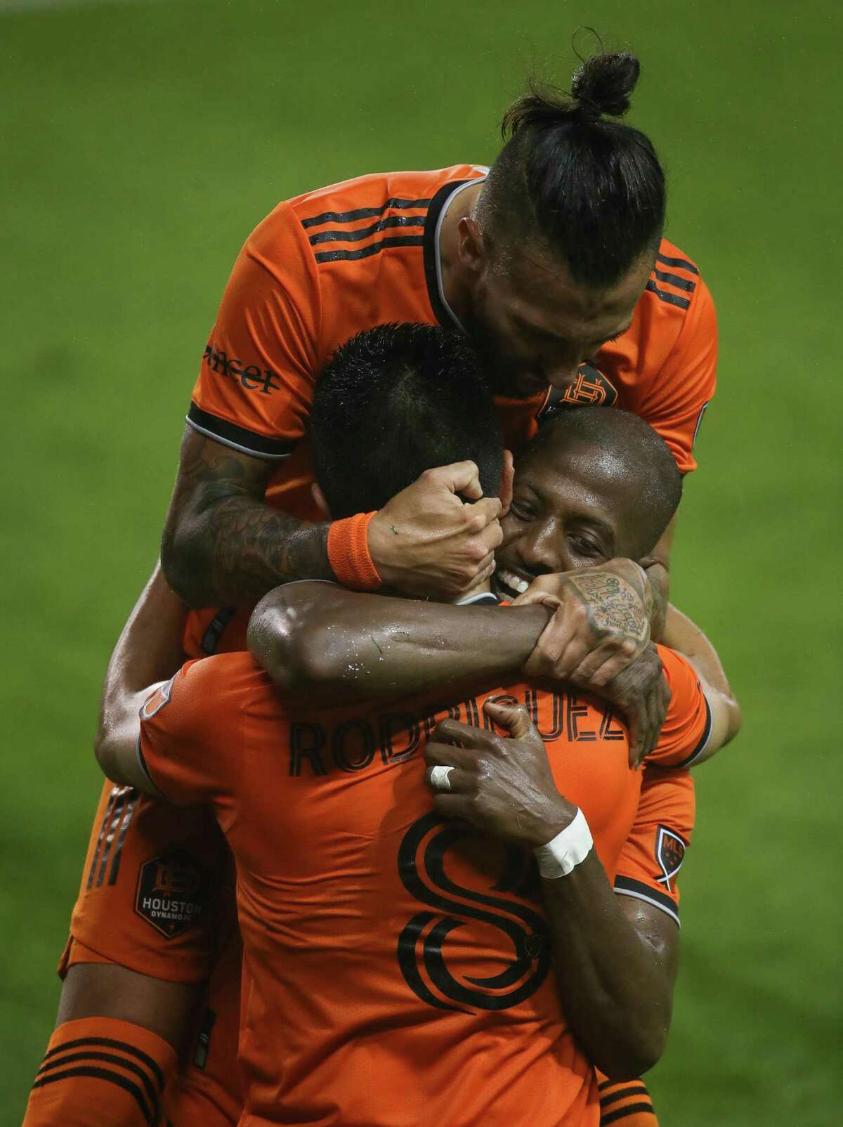 Houston Dynamo FC midfielder Memo Rodriguez (8) is hugged by forward Maximiliano Urruti (37), top, and midfielder Fafa Picault (10) after he scored a goal against the San Jose Earthquakes during the first half of an MLS match at BBVA Stadium on Friday, April 16, 2021, in Houston.