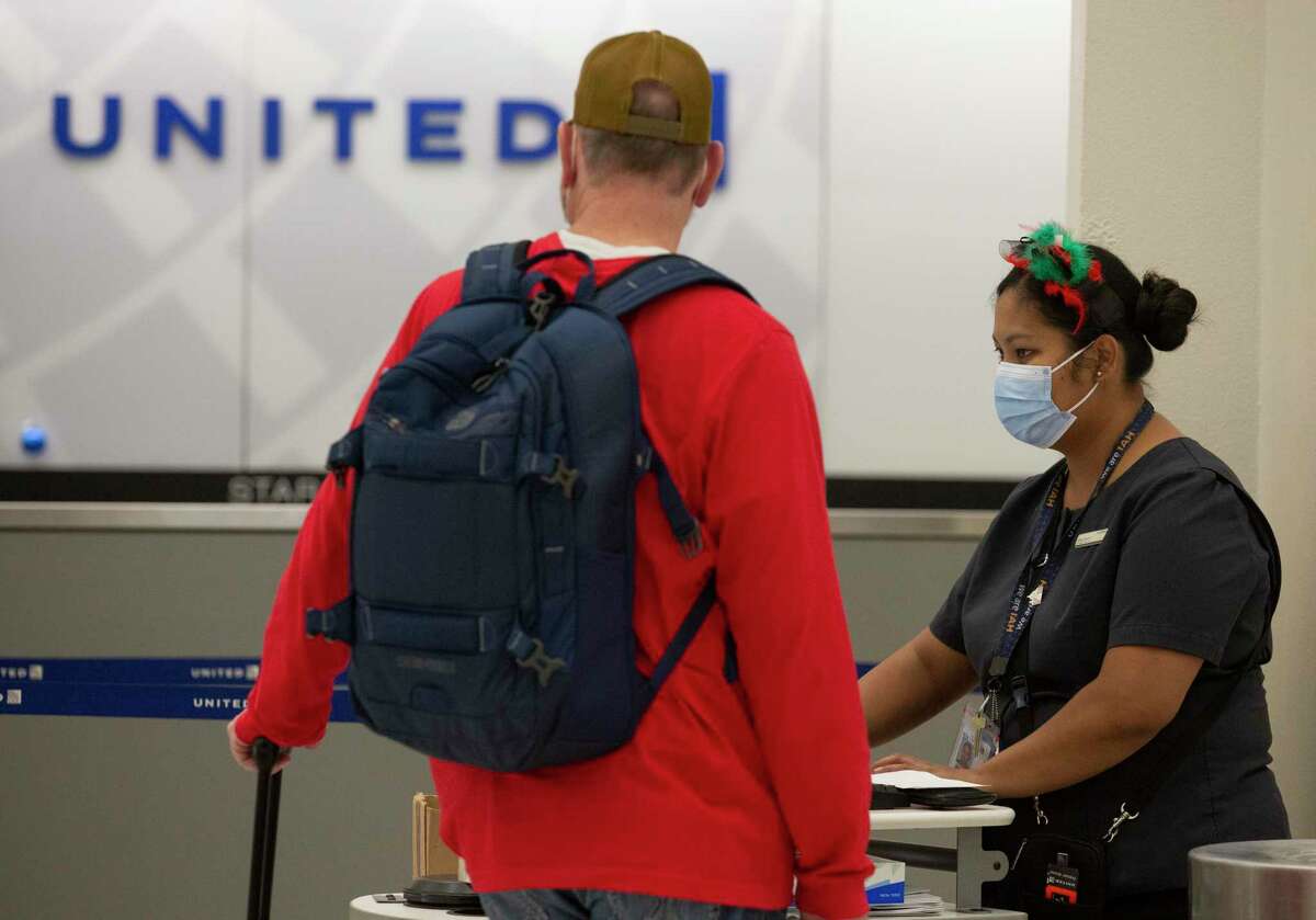 A United Airlines employee helps a passenger checking in Friday, Dec. 24, 2021, at George Bush International Airport in Houston.