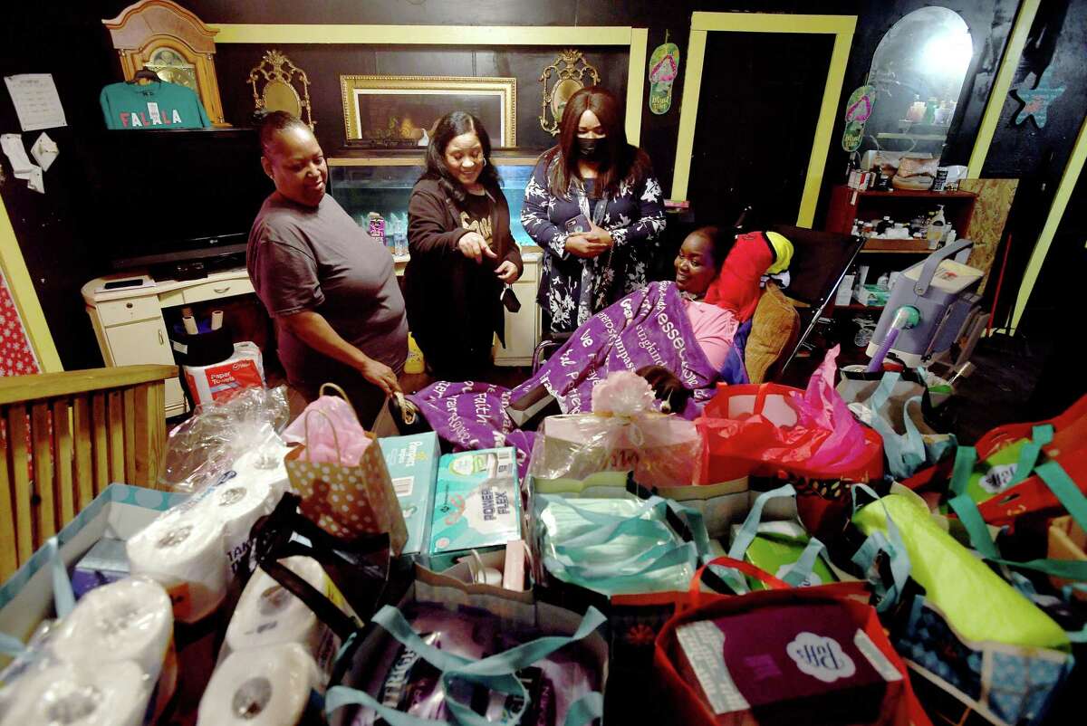 It Takes A Village Beaumont's Sheryl Richard-Jackson and Shirley Chachere look over the mound of bagged gifts with Jasmine Hamilton and her mother Erin Turner (far left) as they deliver gifts and monetary donations raised for the family this Christmas to their home in South Park Monday. Twenty-year-old Hamilton was left a paraplegic after being struck by a hit and run driver in March of 2020. Photo made Monday, December 20, 2021 Kim Brent/The Enterprise