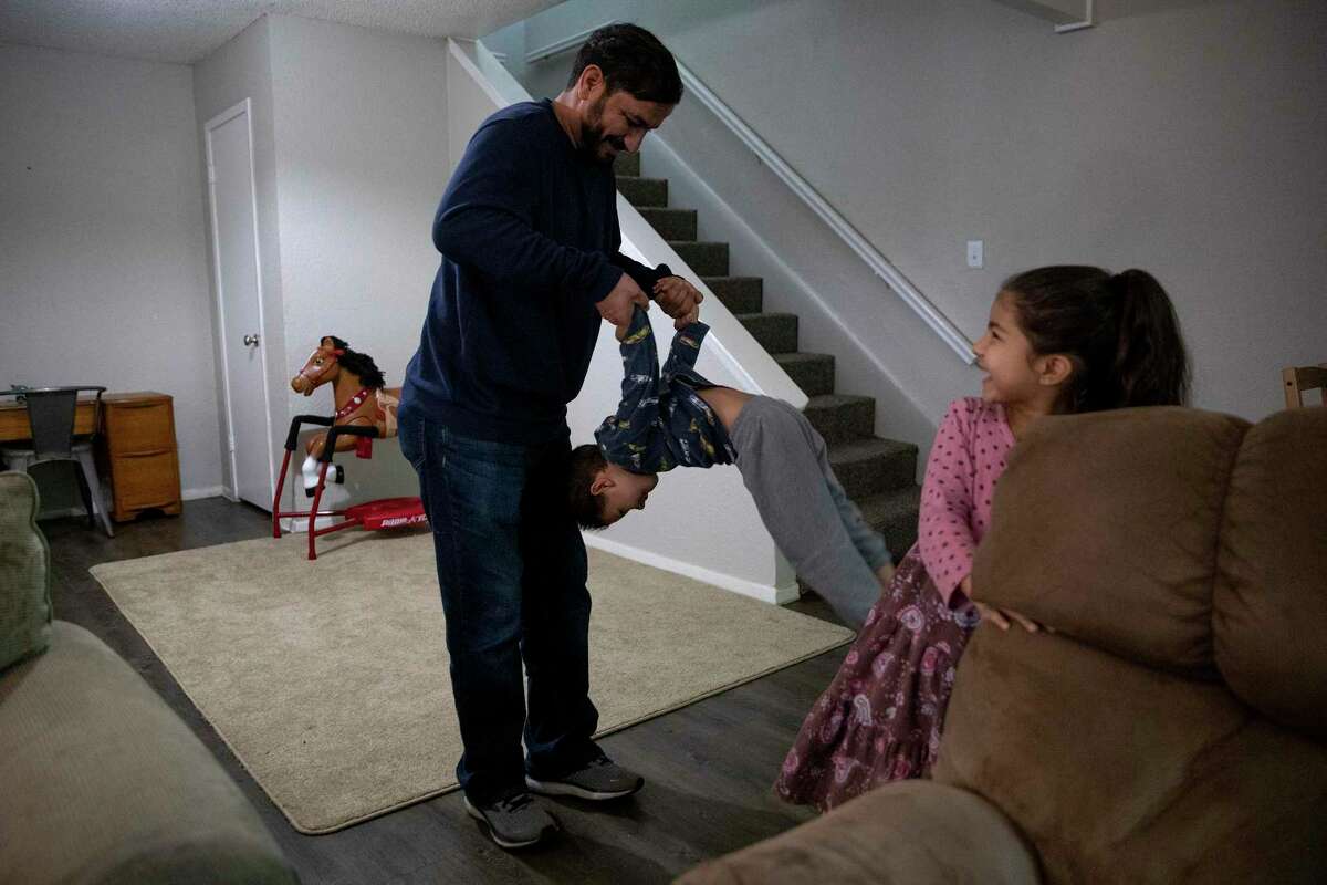 Aimal Amin, who was able to flee Afghanistan with his family after Kabul fell, flips his son Rihanullah, 5, in their San Antonio apartment while his daughter, Zala, 7, watches and laughs.