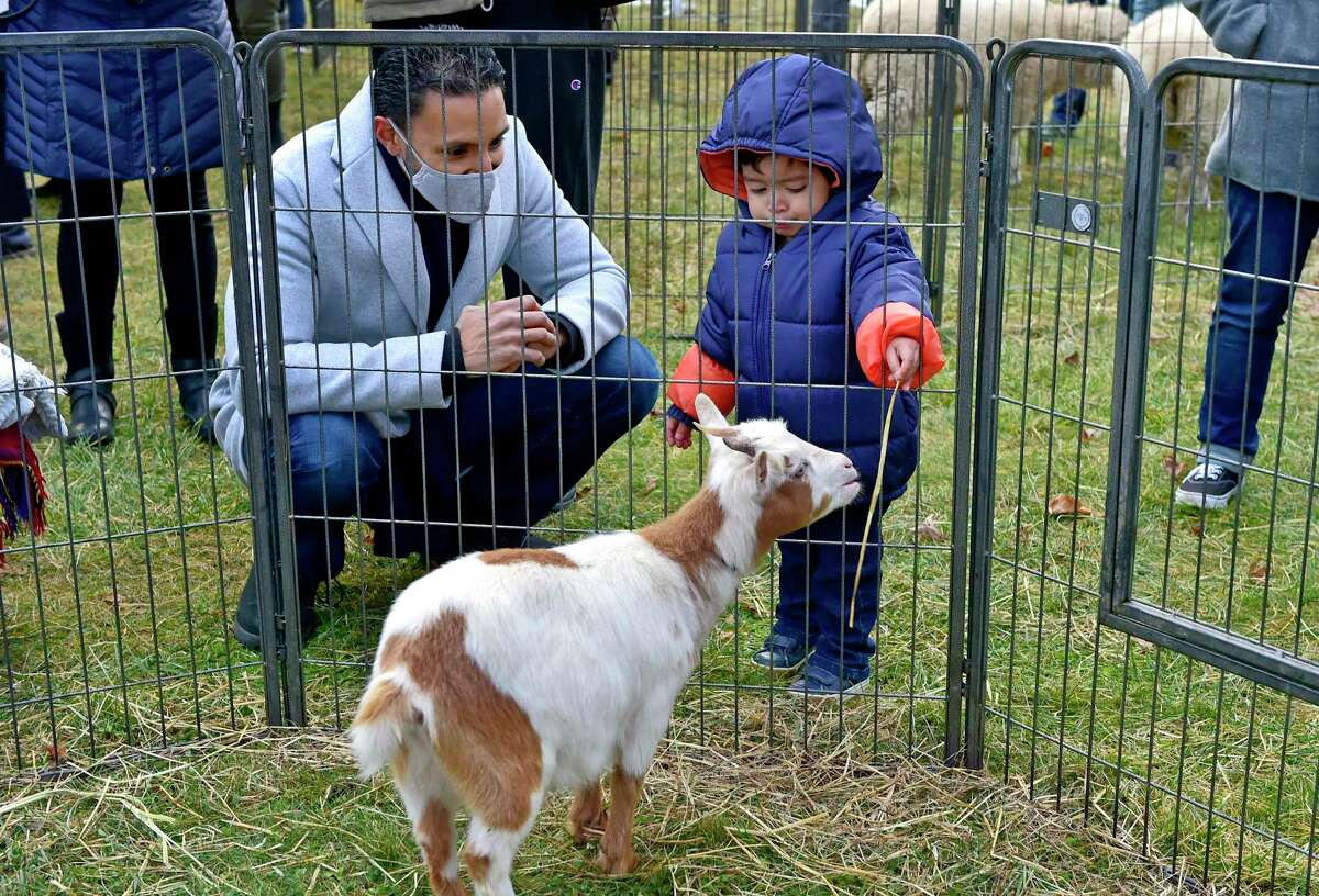 Alberto Vazquez looks on as his son Tony, 2, feeds a baby goat during Second Congregational Church's Outdoor Christmas Pageant and Petting Zoo in Greenwich, Conn., on Friday December 24, 2021. "The hope and joy of Christmas lift our spirits in any year," says Senior Minister Maxwell Grant. "We wanted to make sure we offered a safe way for friends to gather, and for kids to keep teaching us the story."
