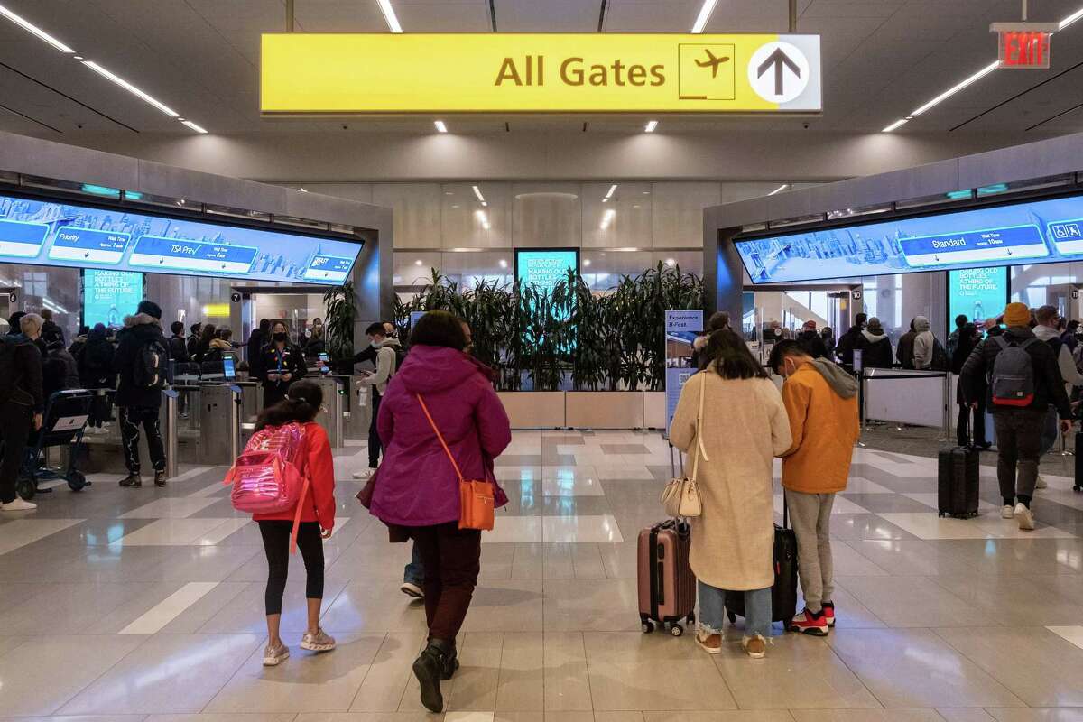 Travelers walk to a security check point at LaGuardia Airport in New York on Dec. 24, 2021. On Christmas Eve, airlines, struggling with the omicron variant of COVID-19, have canceled over 4,000 flights globally.