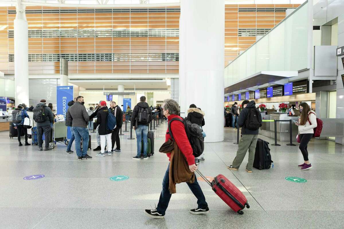 Passengers wait in line at the United Airlines check-in counters at the international terminal at SFO on Friday, December 24, 2021, in San Francisco, Calif.