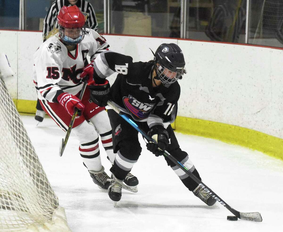 Maya Sherman (18) of the Stamford/Westhill/Staples co-op girls ice hockey team skates with the puck while New Canaan's Caitlin Tully (15) pursures during a game against New Canaan at the Darien Ice House on Saturday, Dec, 18, 2021.