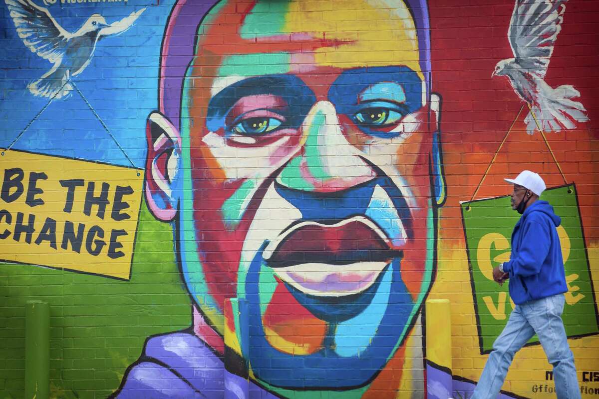 FILE ?‘ A man on April 19, 2021, walks past a mural in Houston depicting George Floyd, whose death touched off a national debate over race and policing in 2020. Floyd?•s 2004 conviction on drug charges, which was brought by a former Houston narcotics officer now at the center of a policing scandal, will be set aside, if the governor approves. (Montinique Monroe/The New York Times)