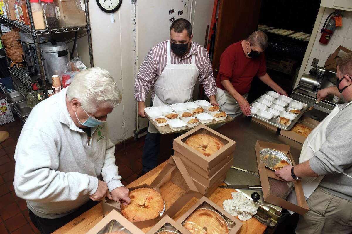 Clockwise from left, Louis Spezzano, Kevin McFadden, Ed Cofone and Mike DeVittorio slice and package apple pie for a Christmas dinner at the Knights of Columbus Orinoco Council #39 at 37 W. Putnam Ave., in Greenwich, Conn., on December 25, 2021. Volunteers prepared 166 meals most of which were delivered.