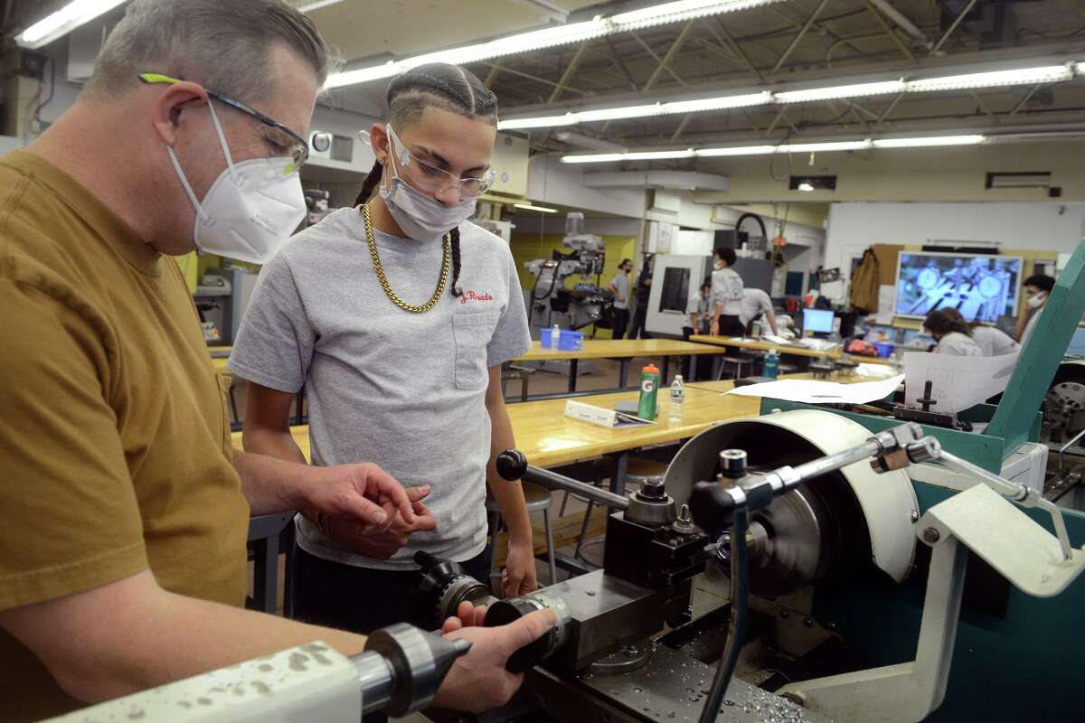 Joe Jannetty, left, works with sophomore Jovanni Rosado, of Bridgeport, during a precision-machining class at Platt Technical High School, in Milford, Conn., on Nov. 17, 2021.