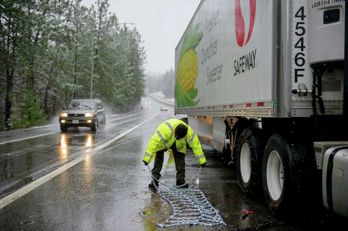 Juan Romero of Merced puts chains on a truck on Interstate 80 near Colfax. Dangerous wind and snow conditions prompted closure of the highway and Highway 50 going up to the Tahoe area.