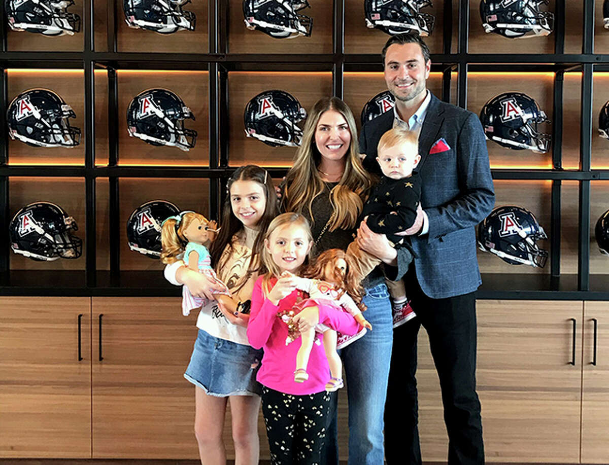 Edwardsville graduate Jimmie Dougherty, his wife Harper and their children Collins, Ellie and Maverick, pose in front of a trophy case at the University of Arizona, where Dougherty recently finished his first season as the passing game coordinator and quarterbacks coach.
